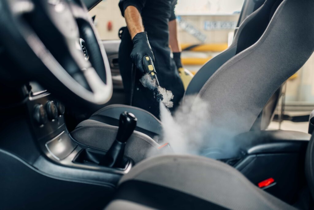 A professional detailing specialist performing deep interior car steam cleaning in Ocala, FL.