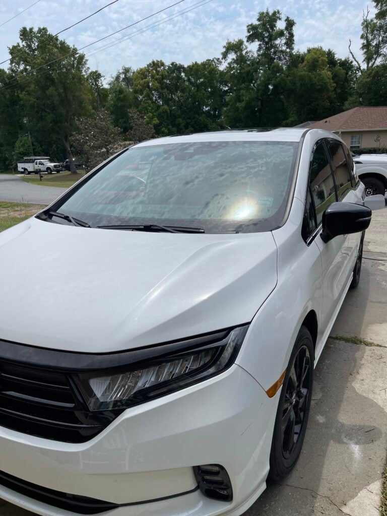 technician performing a full car detail near me on a sedan in an Ocala driveway